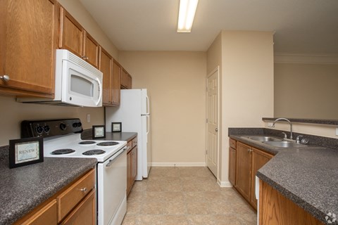 Designer kitchen with oak cabinetry and white appliances at The Columns at Oakwood, Georgia